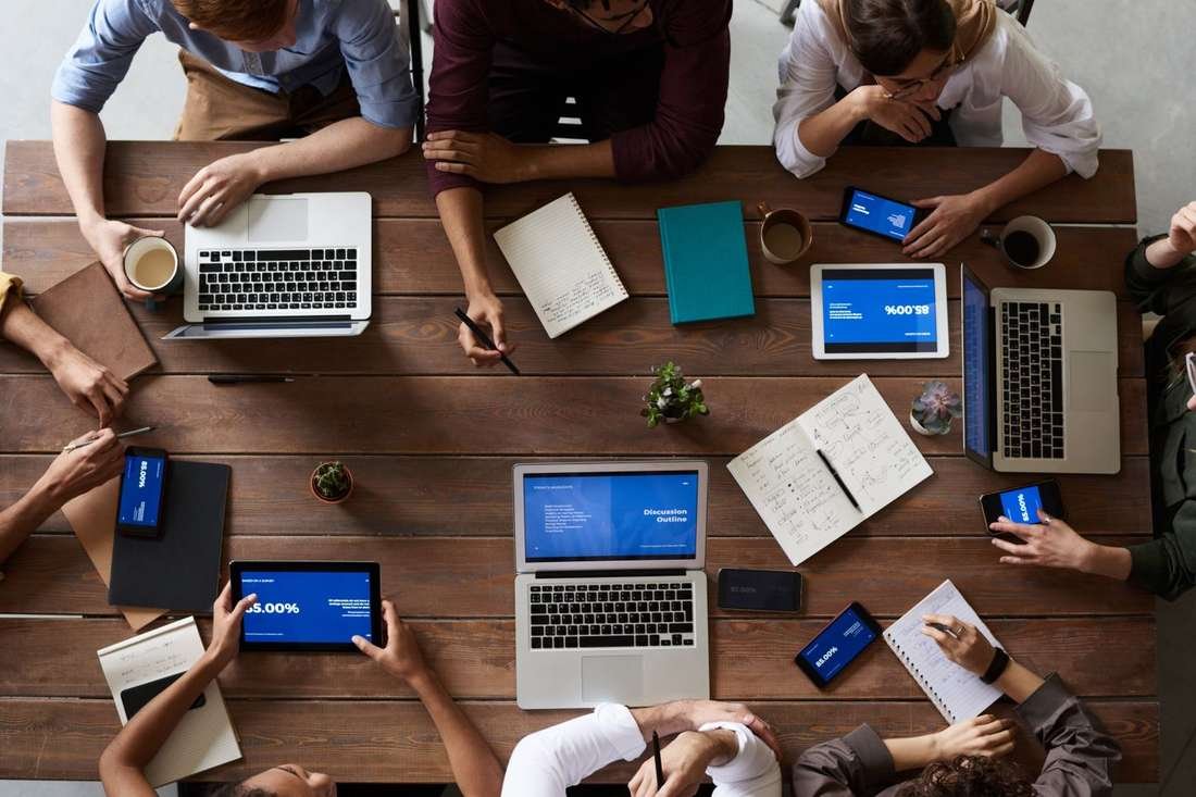 Team working around a table with laptops and tablets